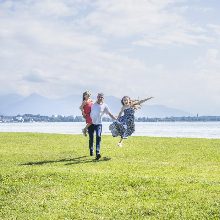 Eine Familie spaziert beim Bodensee und freut sich über Work-Life-Balance.