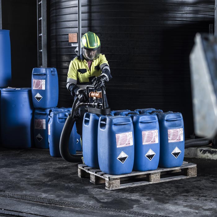Ein Mitarbeiter von Deuring in Schutzkleidung bei der Abfüllung von Textilchemikalien. 